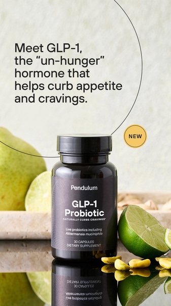 A high-clarity product shot featuring a GLP-1 probiotic bottle surrounded by fresh citrus and nuts against a minimalist, textured background.